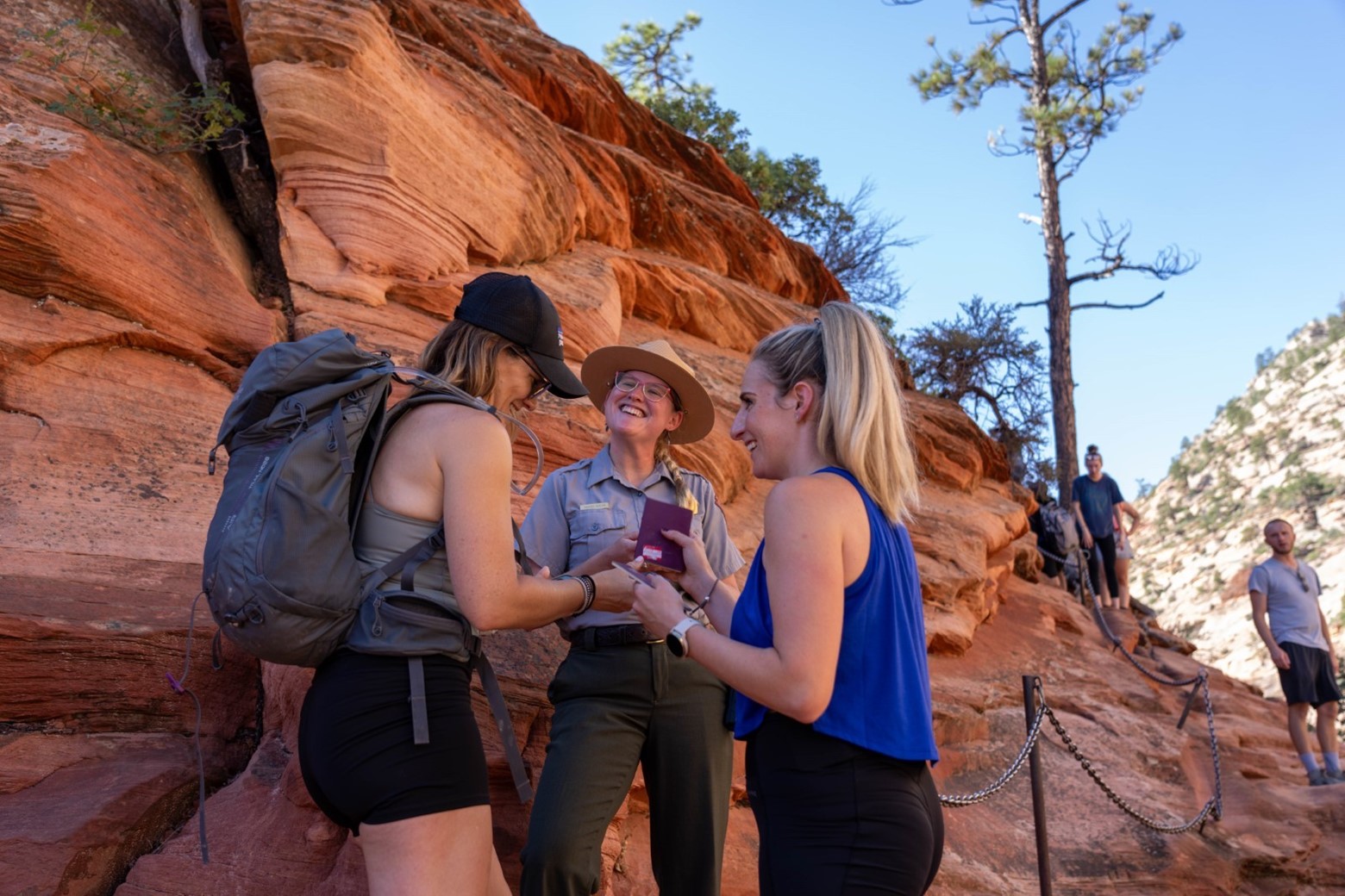 Ranger at Scout Lookout in Zion National Park Two visitors show permits to a smiling ranger at Scout Lookout.