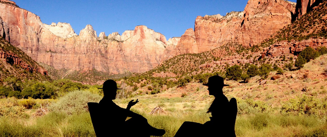 Silhouetted rangers talk in front of the Temples and Towers