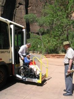 A person in a wheelchair riding a lift to board the shuttle