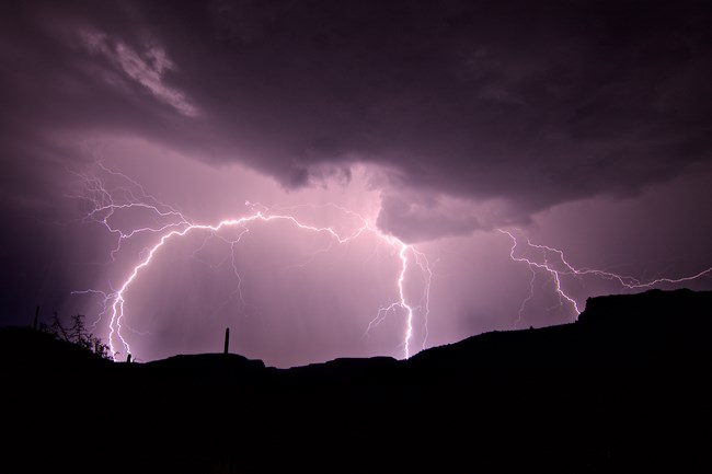 Lightning storm with three bolts in a purple sky