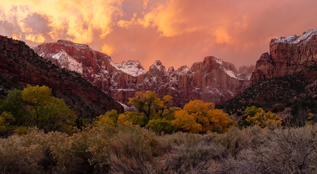Sunset_over_temples Clouds glowing pink, over red cliffs dusted with snow.