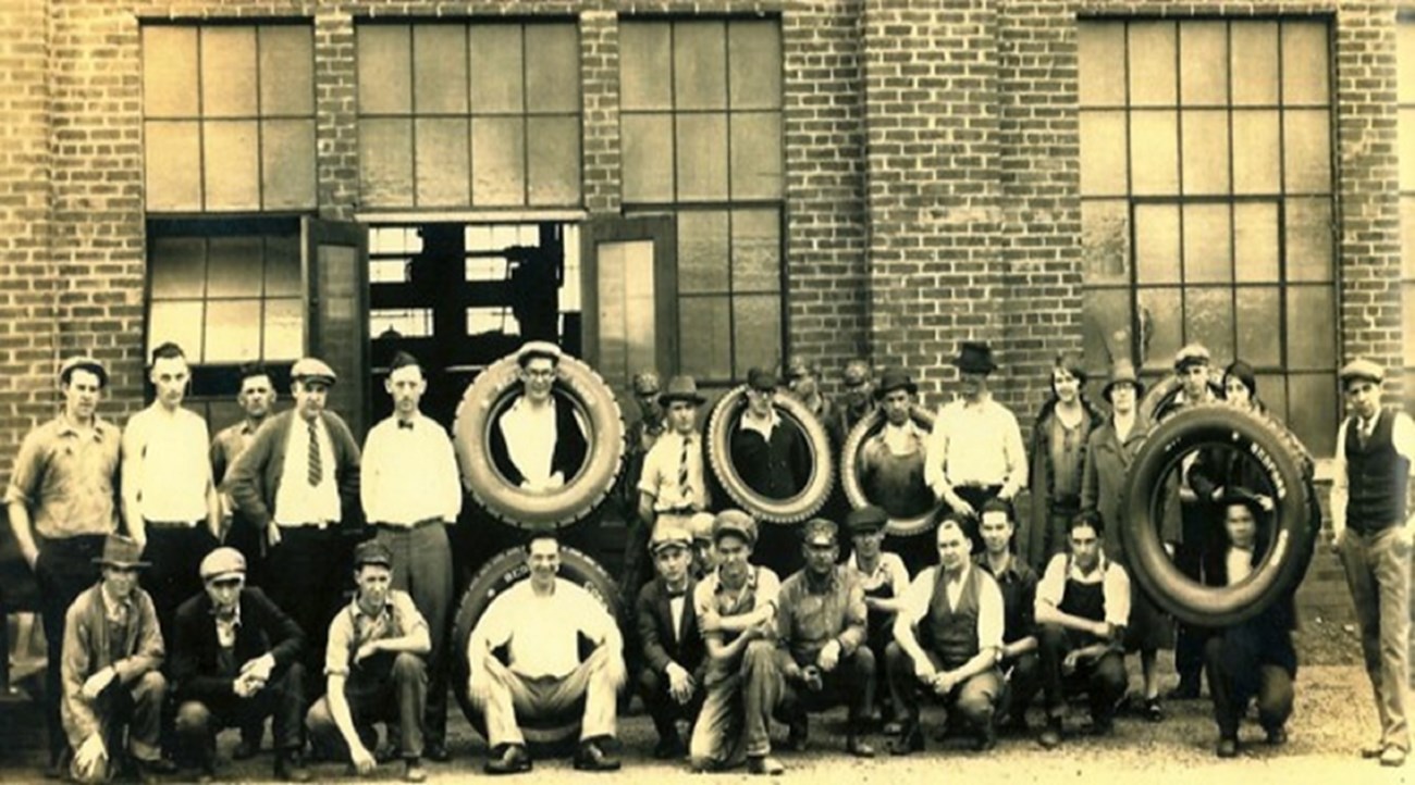 men standing outside of a factory for a formal photo