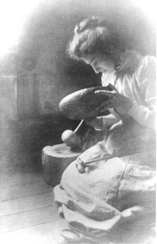 Mary Colter constructing a metal bowl, wearing a calico dress.