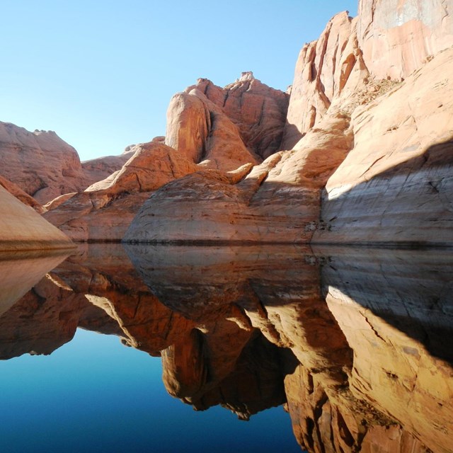 red rock walls and scenic vistas reflected off of a lake