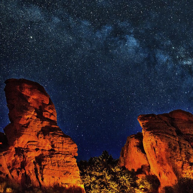 Two large red sandstone rocks set against a milky way sky.