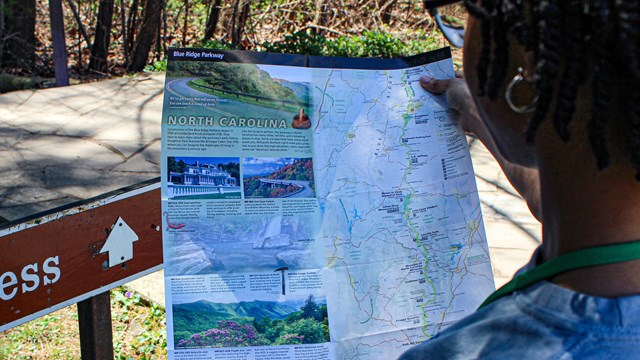 A woman standing outdoors looking at a handheld map