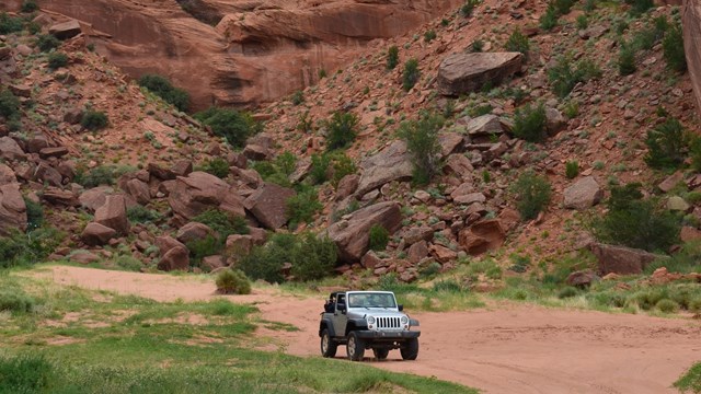 Off road vehicle driving through bottom of canyon.