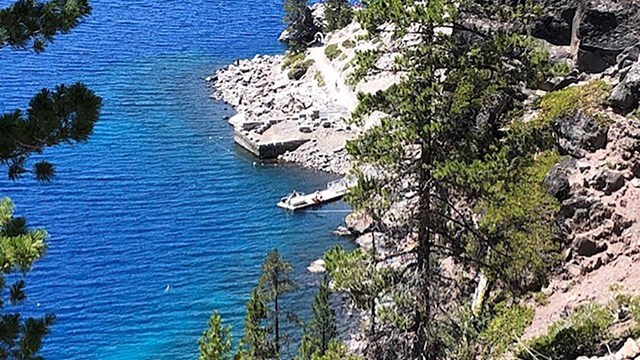 An treetop view of the Cleetwood Cove section of Crater Lake with boat dock trail.