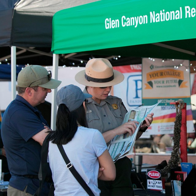 Ranger pointing at paper map with two people