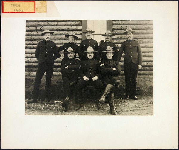 Eight uniformed mounties pose for a photo